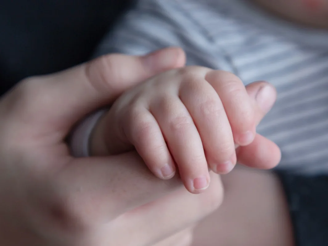 Holding a baby's hand to represent trauma from a birth injury