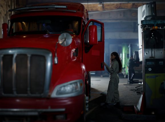 a woman next to a red truck inside an old garage